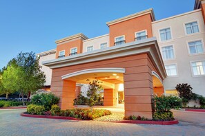 A hotel entrance with a modern design, featuring a prominent archway and a landscaped garden area. - Embassy Suites by Hilton Valencia (Valencia)