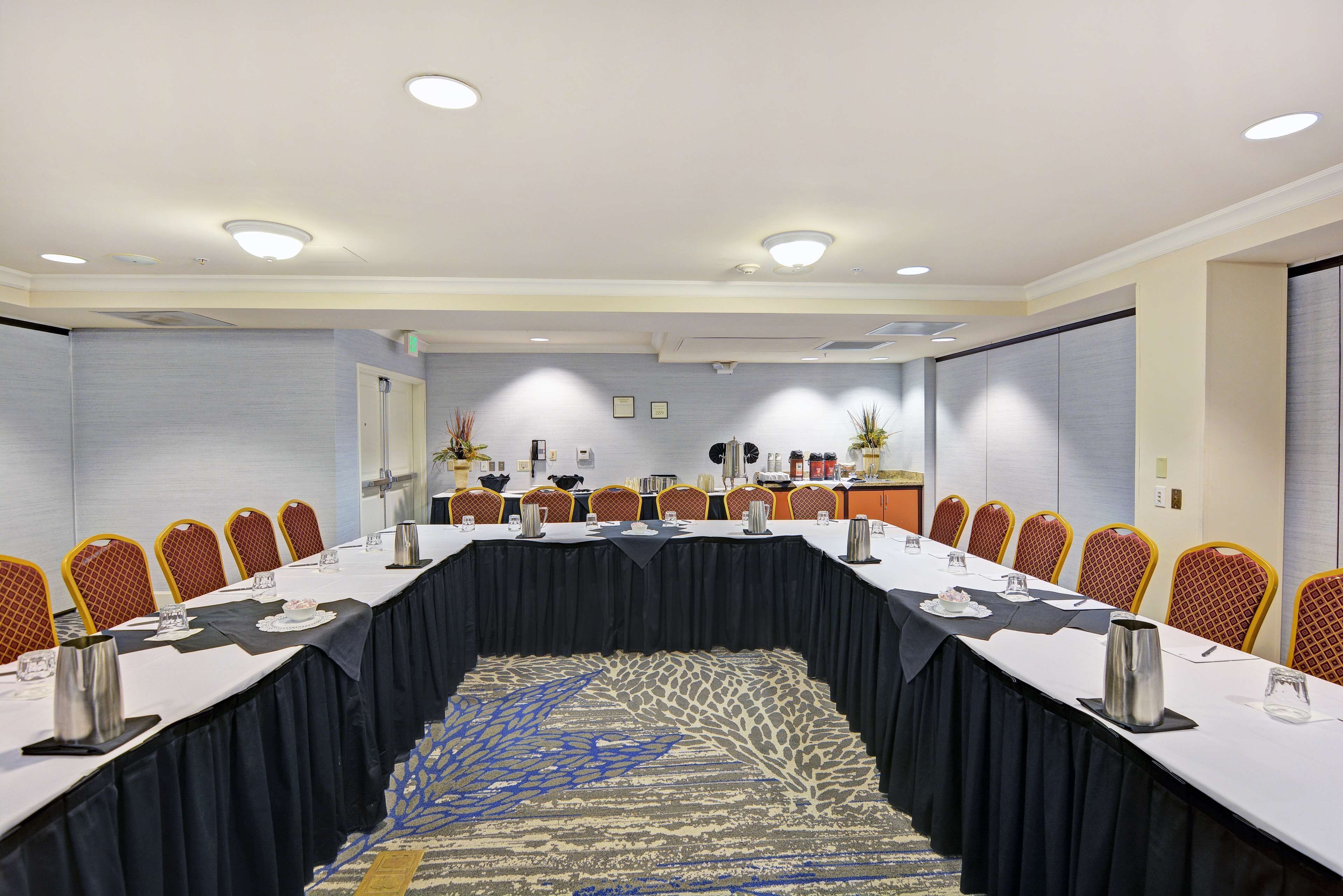 A conference room with a long table, chairs, and a carpeted floor.