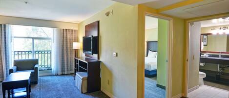 Habitación de hotel con escritorio, silla, televisión y vistas al exterior.