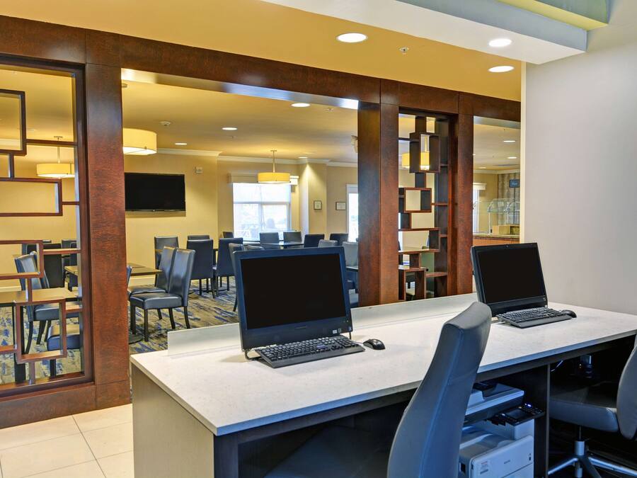 A hotel conference room with two laptops on a table, surrounded by chairs.