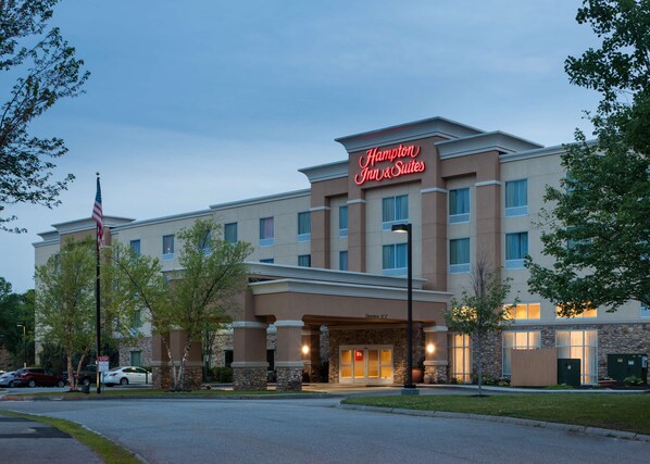 Een Hampton Inn & Suites hotel met een gevel van natuursteen, meerdere ramen en een Amerikaanse vlag.