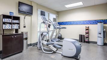 Una palestra con tapis roulant, una cyclette e una panca pesi.