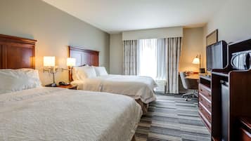 A hotel room with two beds, a desk, a television, and a minibar.