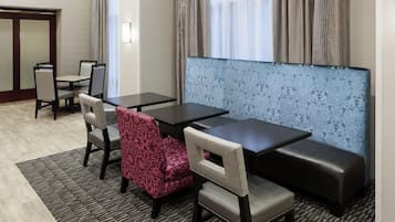 A hotel room with a seating area featuring a sofa and chairs, a small table, and a patterned wall.