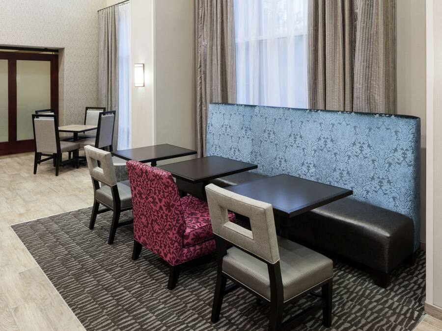A hotel room with a seating area featuring a sofa and chairs, a small table, and a patterned wall.