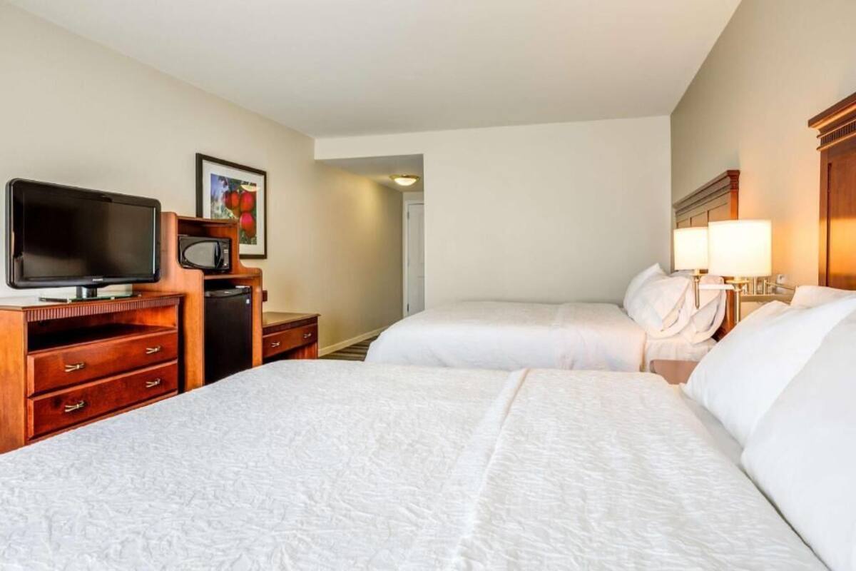 Een hotelkamer met twee bedden, een televisie, een magnetron en een bureau met lades.