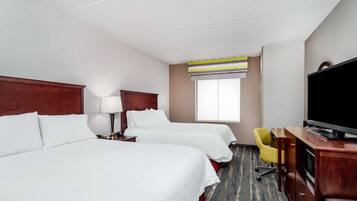 Quarto de hotel com duas camas, televisão, secretária e uma cadeira.