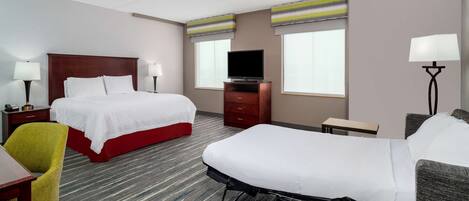 A hotel room with two beds, a TV, a desk, and a chair.