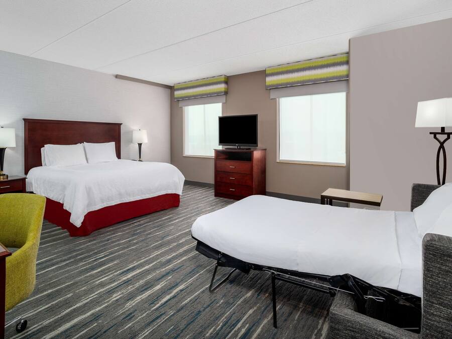 Habitación de hotel con dos camas, un televisor, un escritorio y una silla.