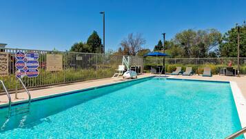 A clear blue pool with a fenced area, lounge chairs, and a lifeguard stand.