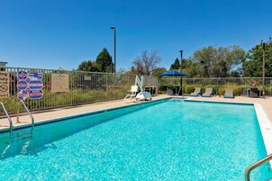 Una piscina al aire libre, sombrillas, sillones reclinables de piscina