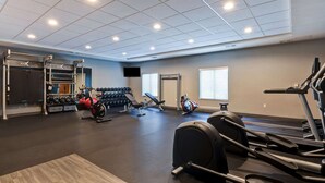 Een fitnessruimte met cardioapparatuur, krachttoestellen en gewichten.