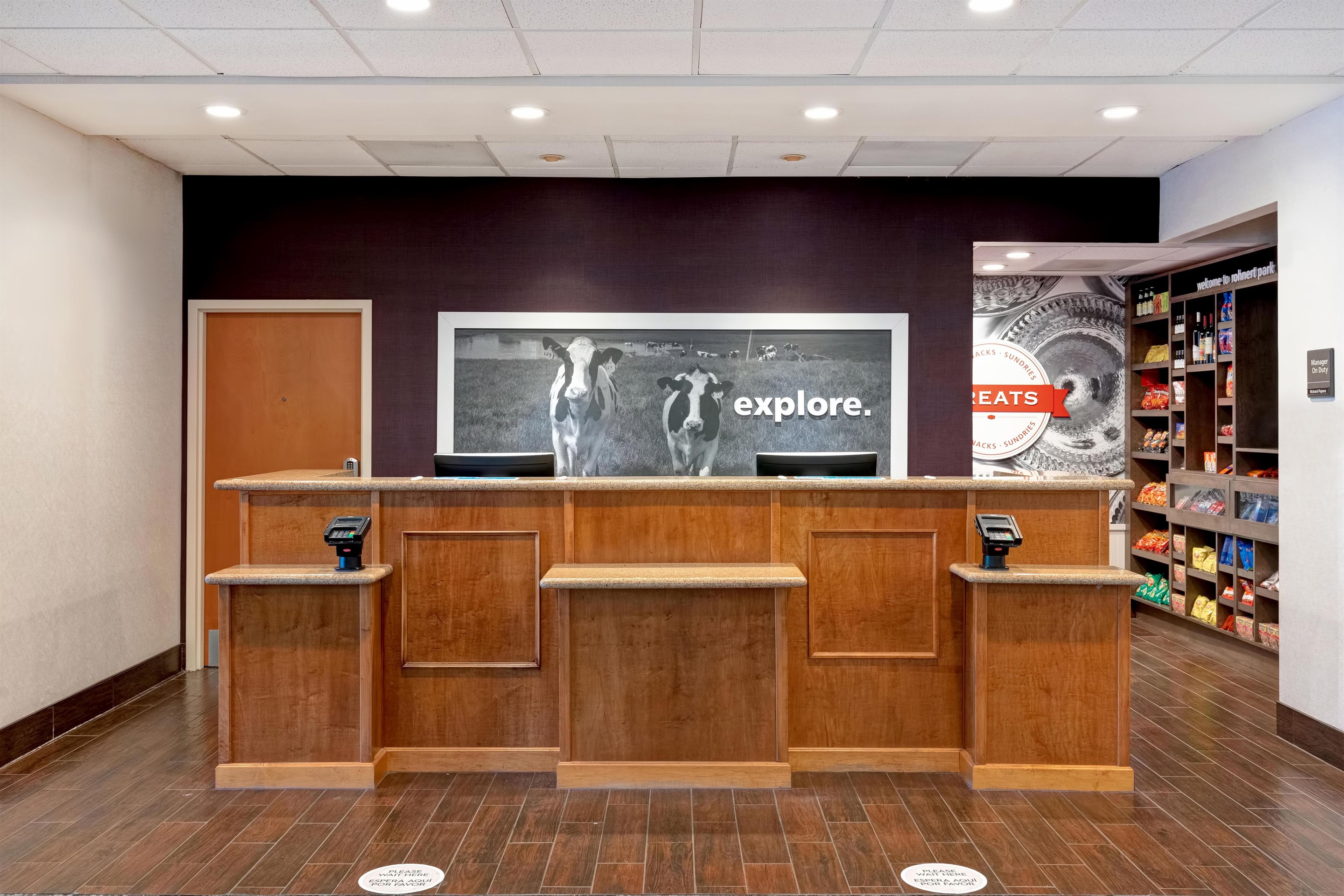 A reception area with a wooden counter, a television screen displaying a cow, and a wall with a 'welcome to roinert park' sign.