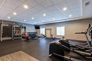 Un gimnasio con diverso equipo de ejercicio, incluyendo cintas de correr y máquinas de pesas.