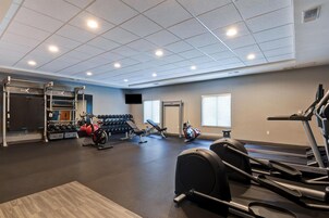 Un gimnasio con diverso equipo de ejercicio, incluyendo cintas de correr y máquinas de pesas.