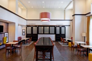 A spacious conference room with a long table and chairs, a large hanging light fixture, and a modern interior design.