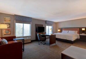 Una habitación de hotel con cama, escritorio, silla y televisor.