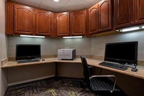 Ein Büro im Eck mit zwei Computern, einem Drucker und einem Stuhl.