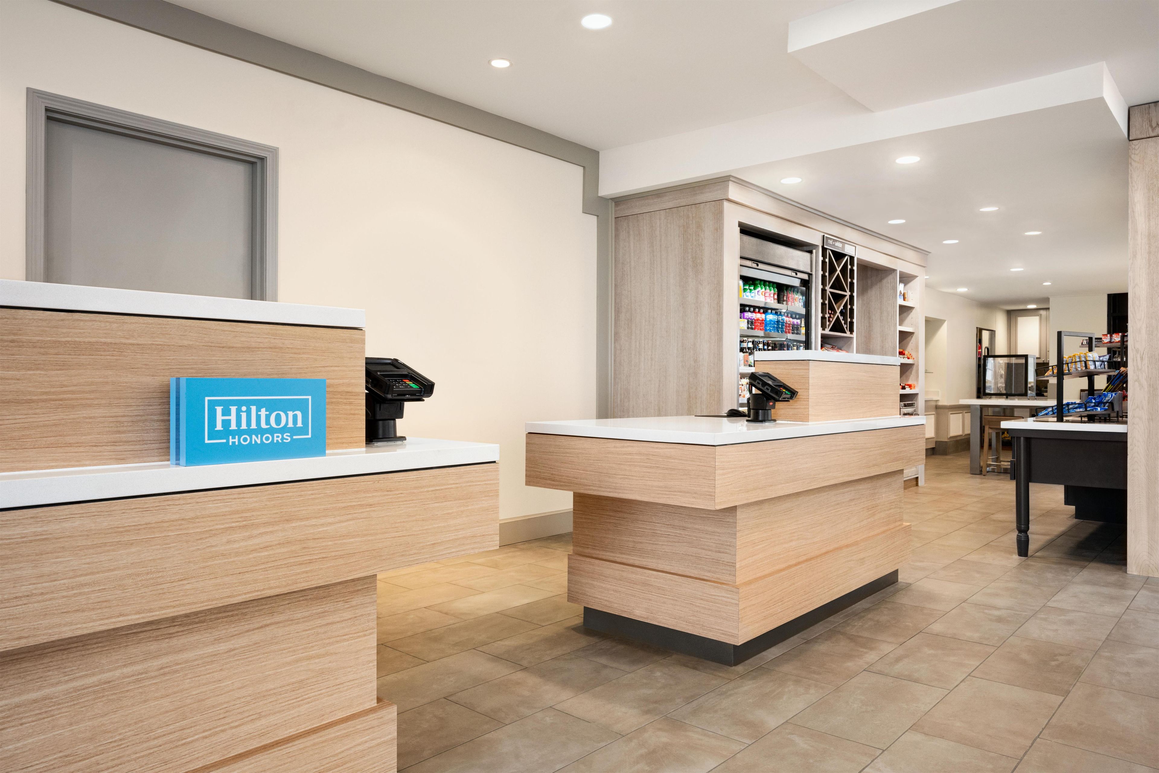 A hotel reception area with wooden reception desks, a blue sign reading 'Hilton Honors,' and a well-lit interior.