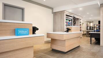 A hotel reception area with wooden reception desks, a blue sign reading 'Hilton Honors,' and a well-lit interior.