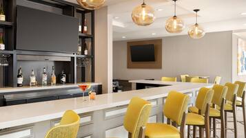 A modern kitchen with a bar area, bar stools, and a large flat-screen TV mounted on the wall.