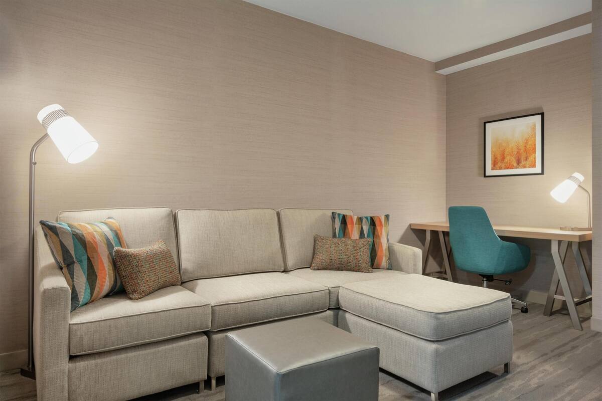 A modern living room with a sectional sofa, a desk, and a chair.