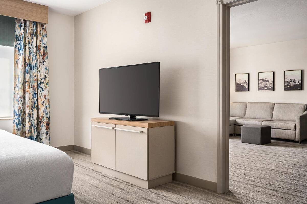 A hotel room with a bed, a TV on a wooden cabinet, a sofa, and a small table.