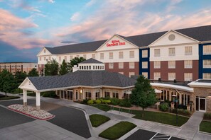 A multi-story hotel with a prominent 'Hilton Garden Inn' sign, a covered outdoor area, and a parking lot. - Hilton Garden Inn Fort Collins (Fort Collins)