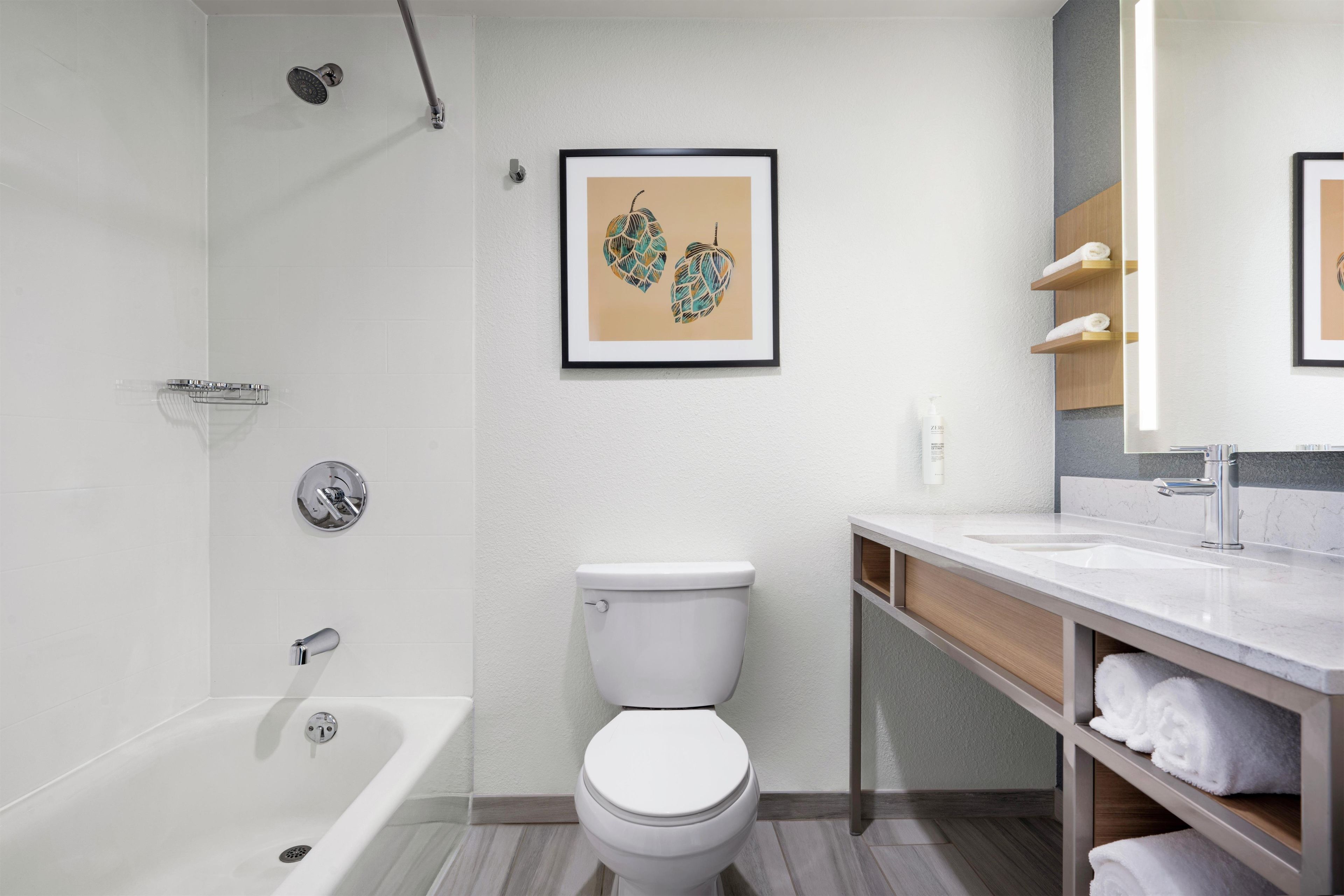 Un baño moderno con bañera, inodoro y tocador con estantes.