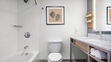 Un baño moderno con bañera, inodoro y tocador con estantes.