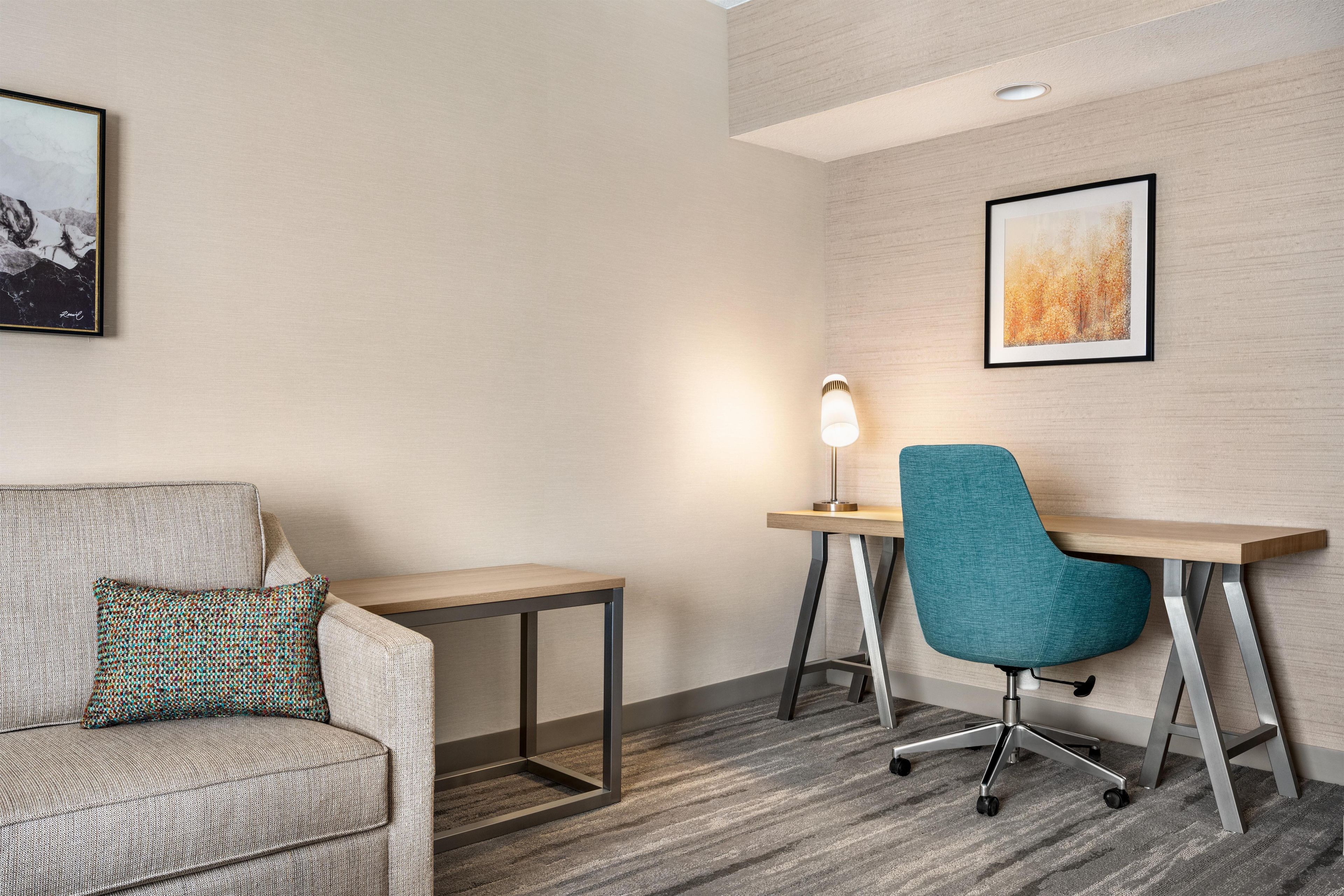 A modern hotel room with a sofa, a desk, and a chair.