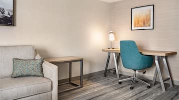 A modern hotel room with a sofa, a desk, and a chair.