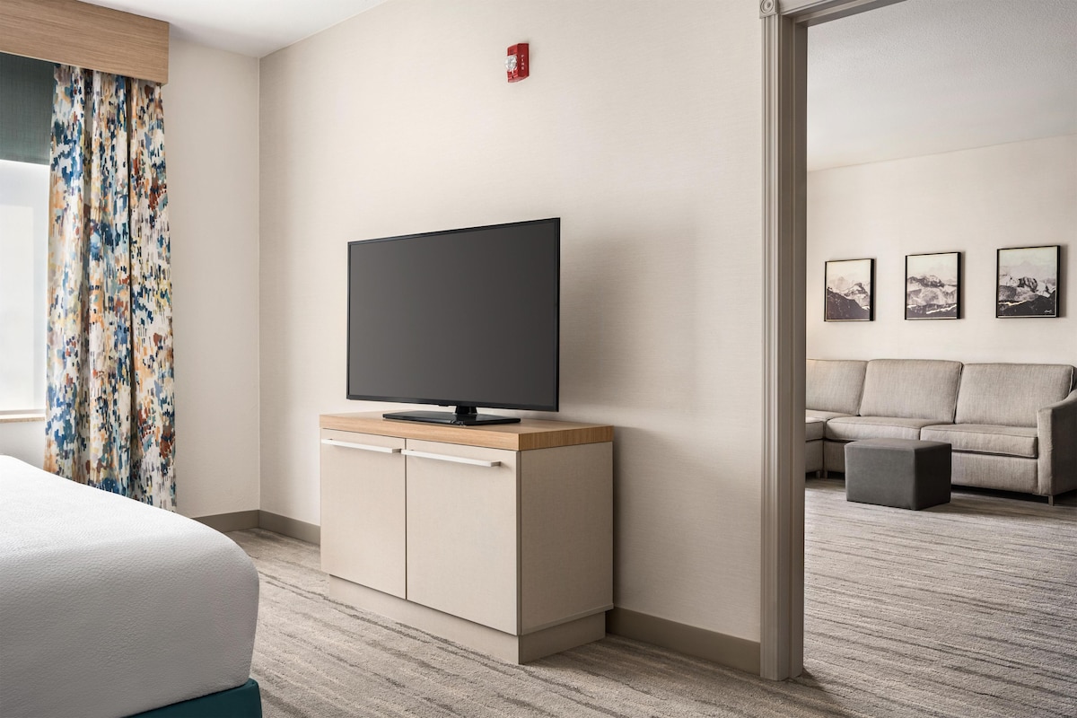 A hotel room with a bed, a TV on a wooden cabinet, a sofa, and a small table.