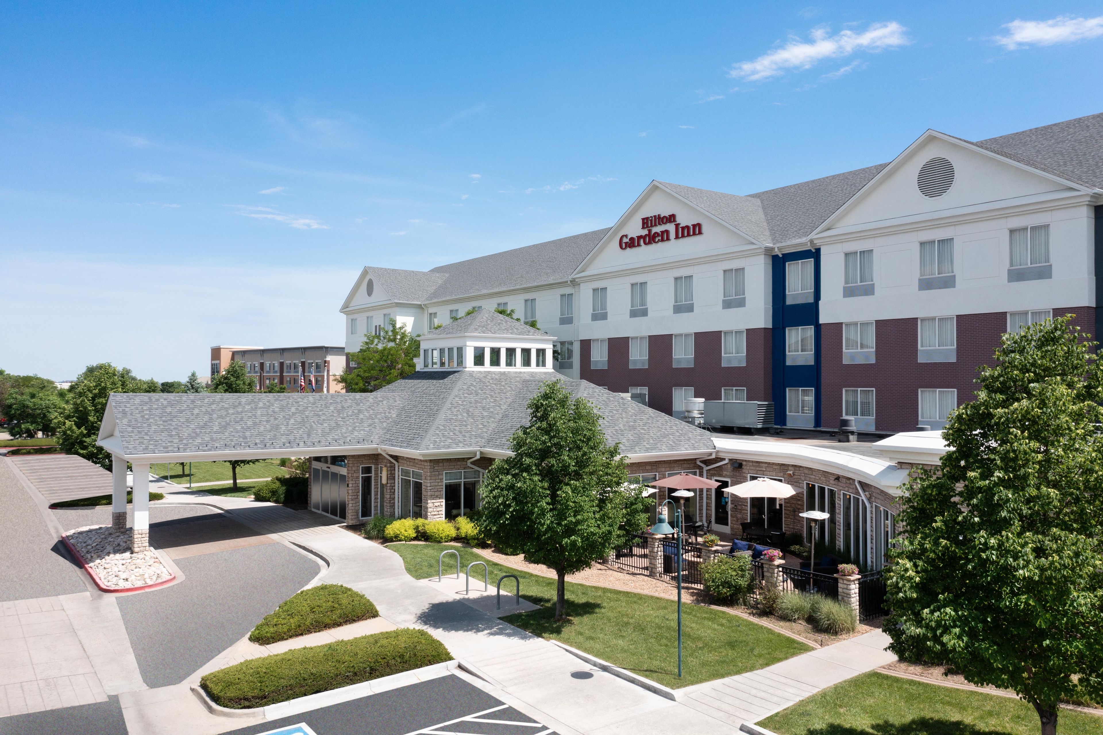 Ein Hilton Garden Inn mit überdachter Außenbereich-Sitzgelegenheit und einem Parkplatz.