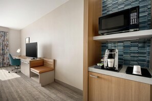 A hotel room with a desk, a television, a microwave, a coffee maker, and a minibar. - Hilton Garden Inn Fort Collins (Fort Collins)