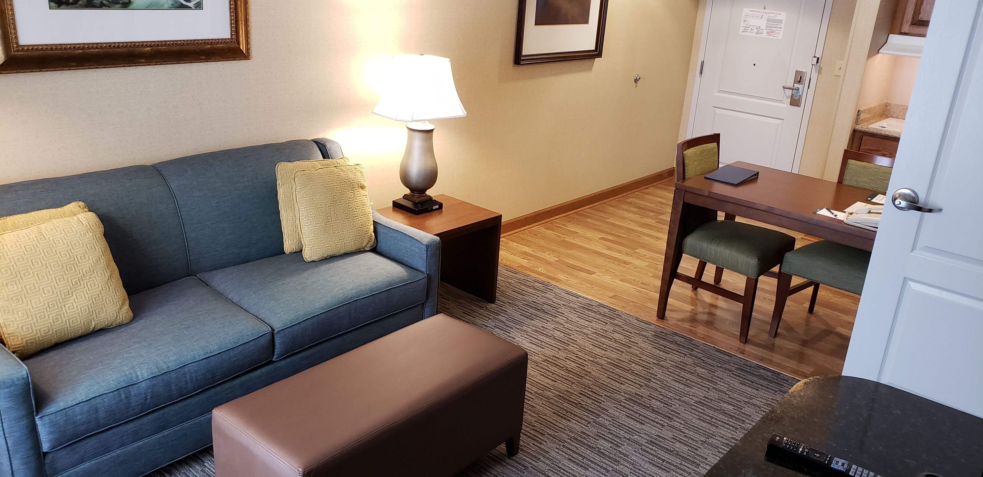 A living area with a sofa, a table, and a lamp.