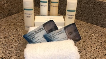 A bathroom counter with Neutrogena products, including a Gentle Cleansing Makeup Remover, and a white towel on a tray.