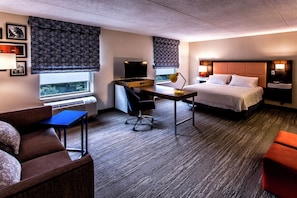 A hotel room with a bed, desk, chair, and a view of the outdoors. - Hampton Inn & Suites Staten Island (Staten Island)