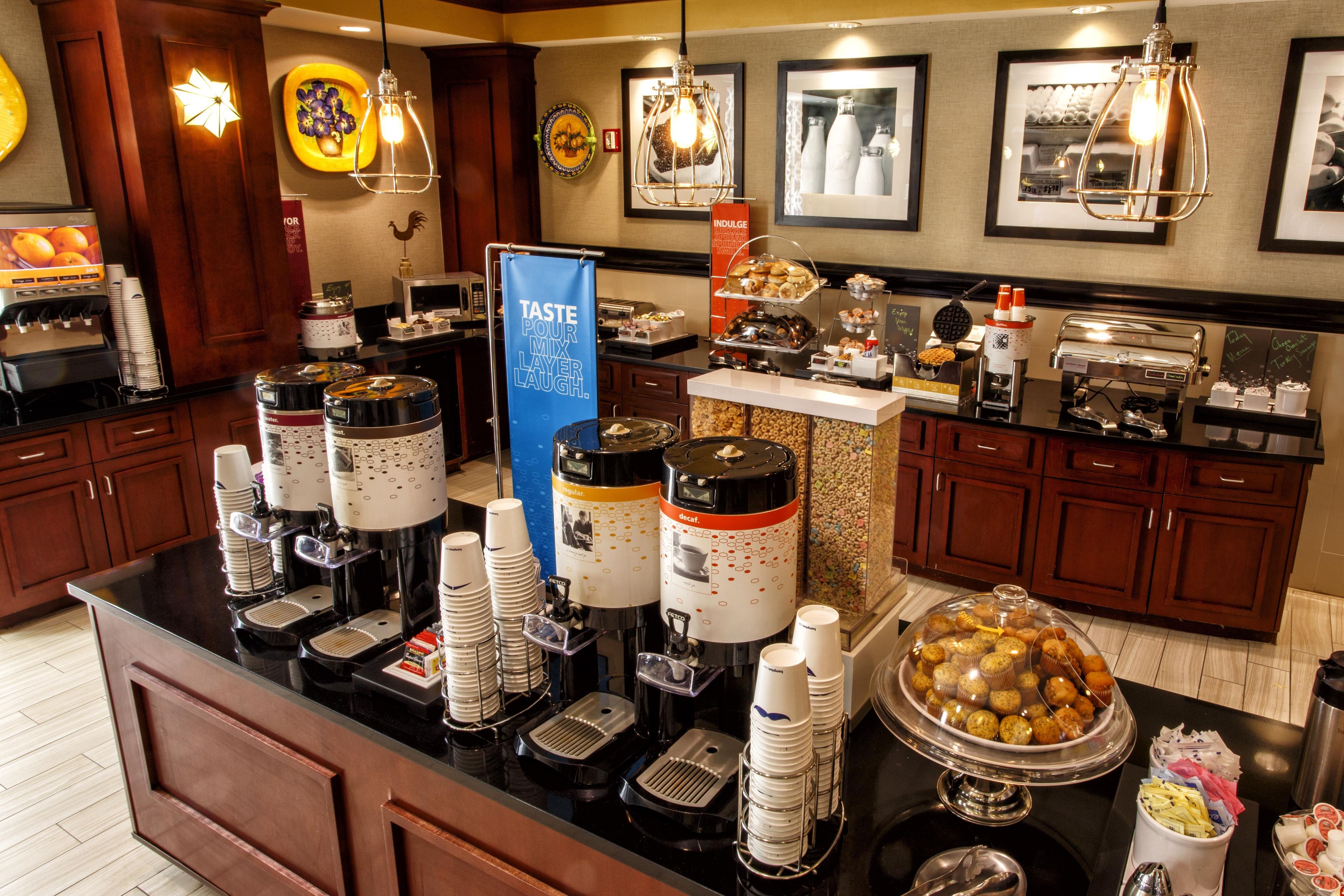 A buffet area with various food stations, including a coffee machine, a decaffeinated coffee option, and a variety of pastries and baked goods.