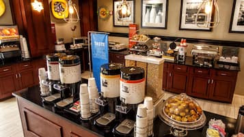 A buffet area with various food stations, including a coffee machine, a decaffeinated coffee option, and a variety of pastries and baked goods.