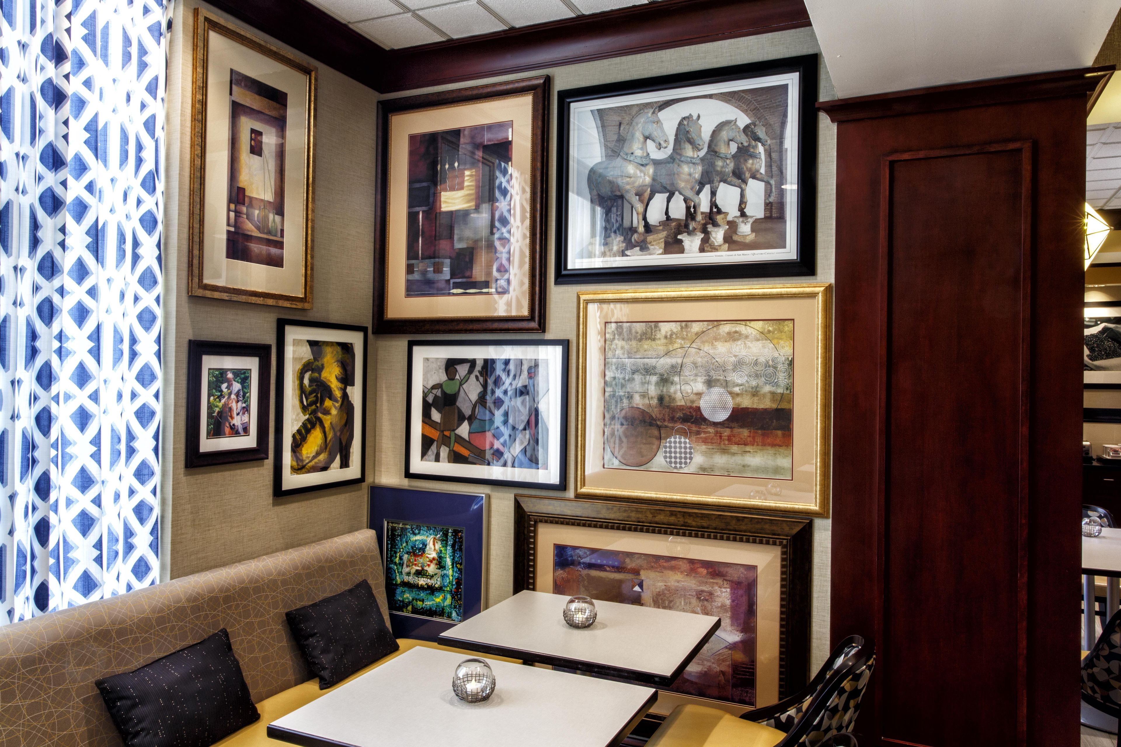 A room with a sofa, a table, and various framed artworks on the walls.