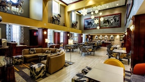 A spacious lobby with a high ceiling, multiple seating areas, and a dining section.