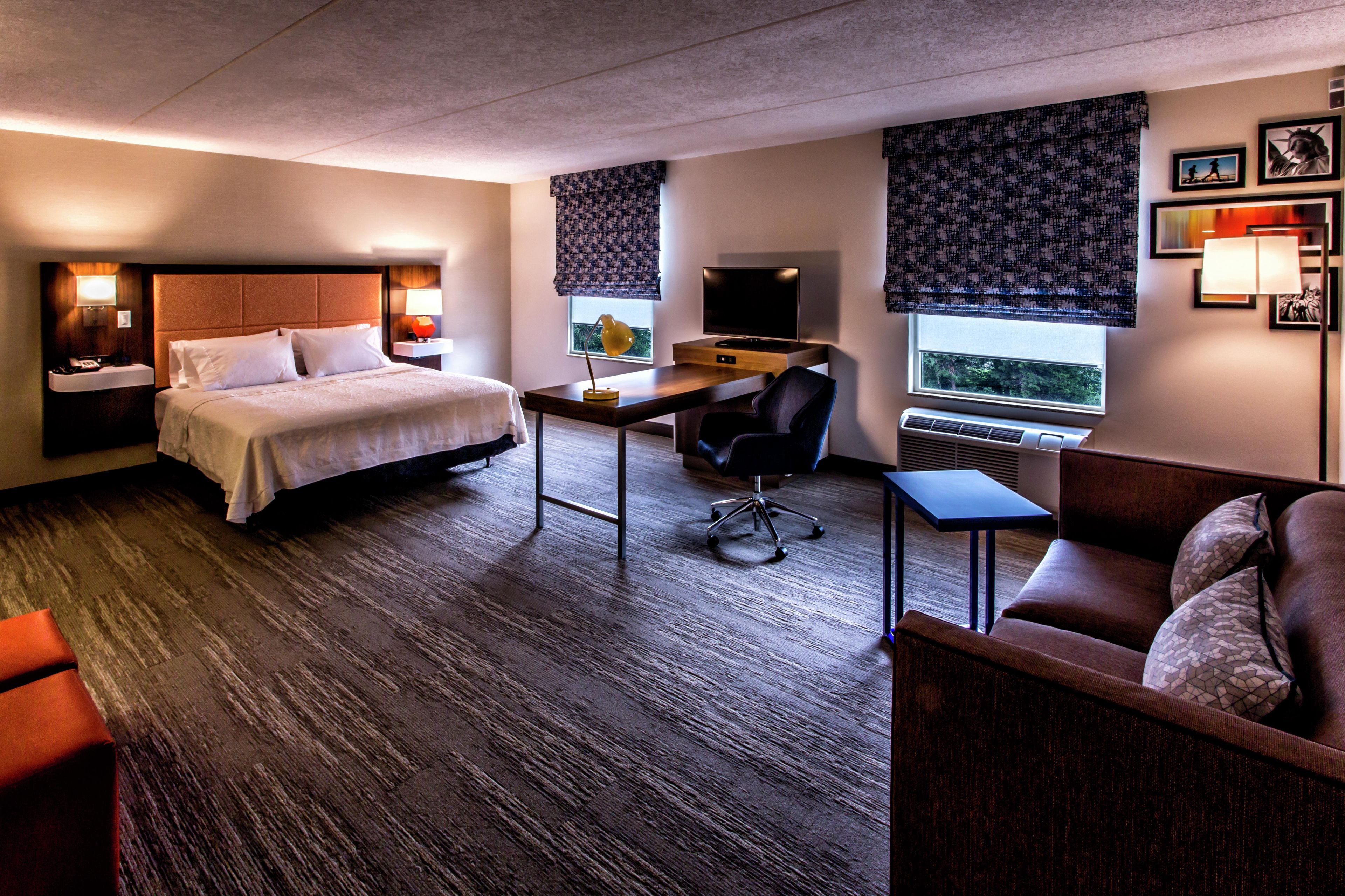 A hotel room with a bed, desk, chair, and a couch.