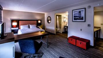 Ett hotellrum med en säng, ett skrivbord, en stol och ett badrum som syns genom en öppen dörr.