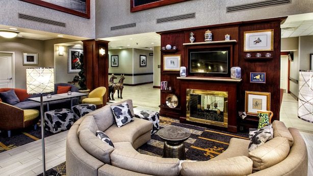 A spacious lobby with a large, curved sofa, a fireplace, and a television.