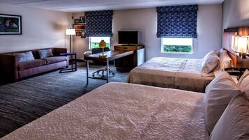 Habitación de hotel con dos camas, un escritorio, un sofá, un televisor y una ventana con vistas.