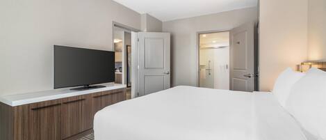 Una habitación de hotel con una cama, un televisor sobre un mueble de madera y una puerta que da a un baño.