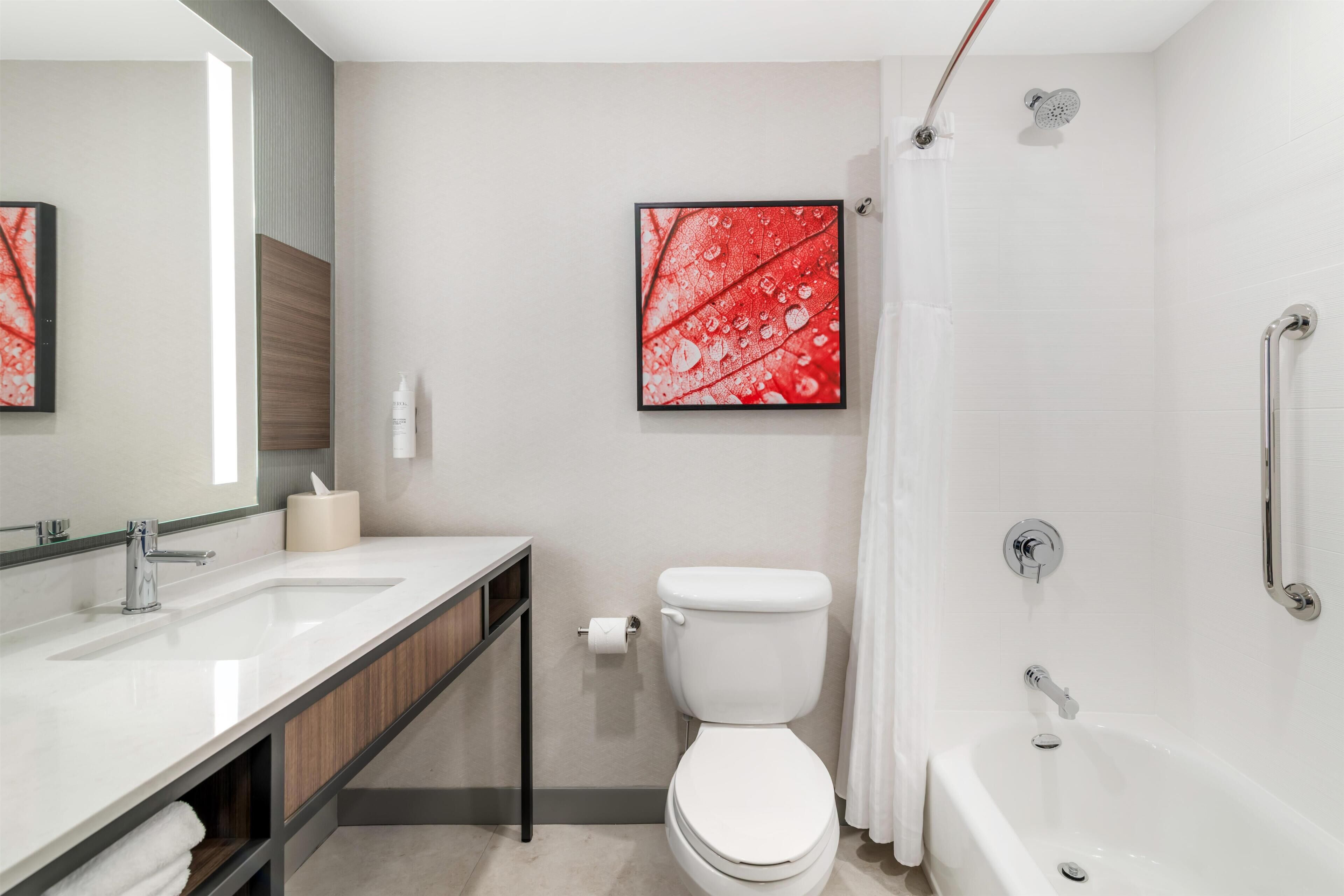 Un baño moderno con lavamanos, inodoro y ducha.