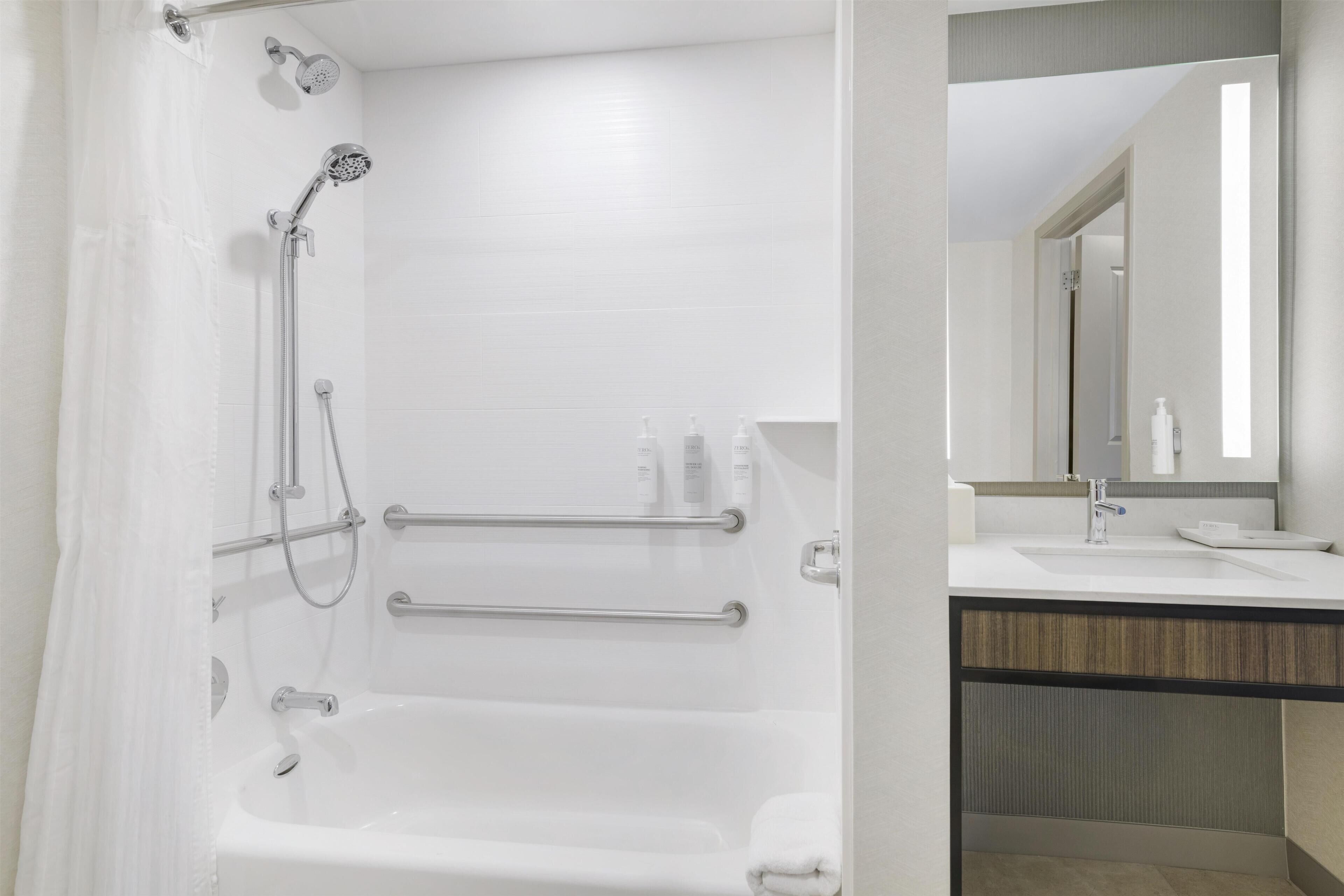 A modern bathroom with a bathtub, shower, and vanity with a mirror.
