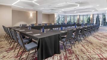 A conference room with a long table, chairs, and a carpeted floor.
